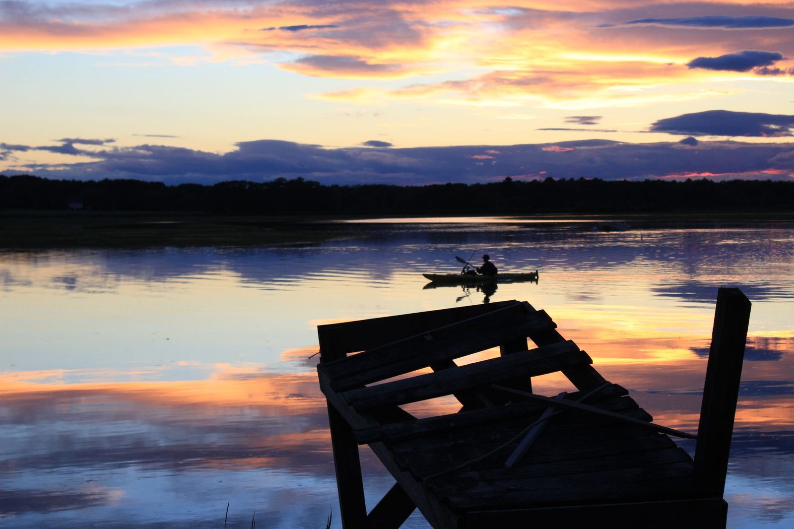 Serene lake view with silhouetted canoeist at sunset in Scarborough, Maine