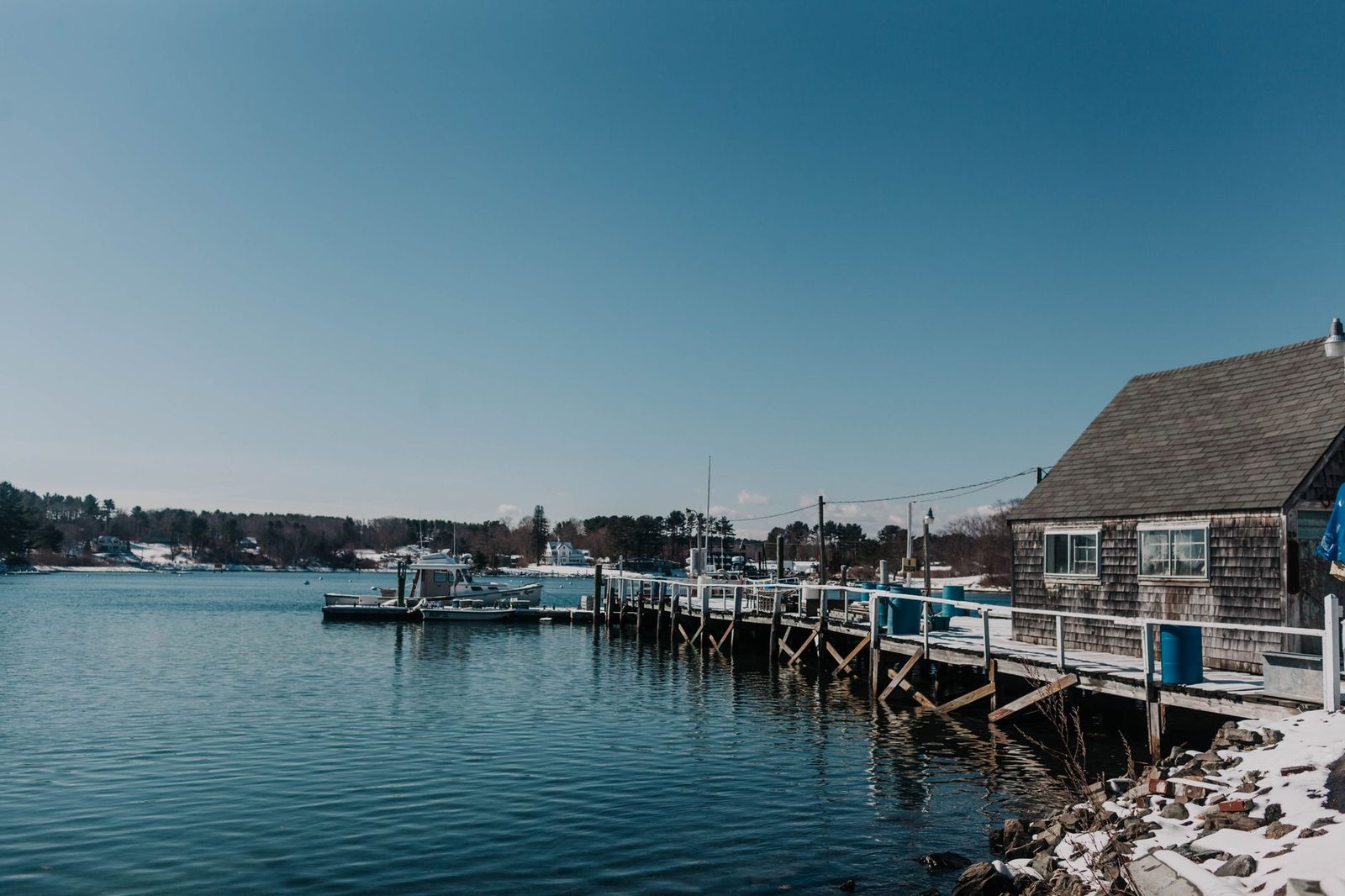 A tranquil winter scene of a dock and snowy shoreline in York, Maine